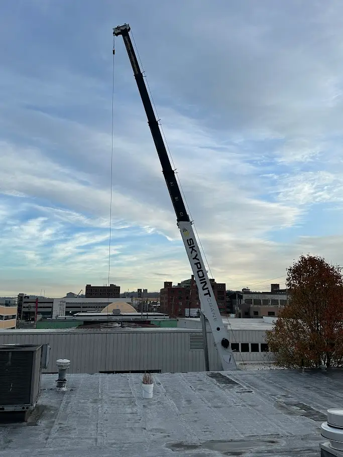 Swing cab crane lifting chiller unit at a commercial building in Cambria County