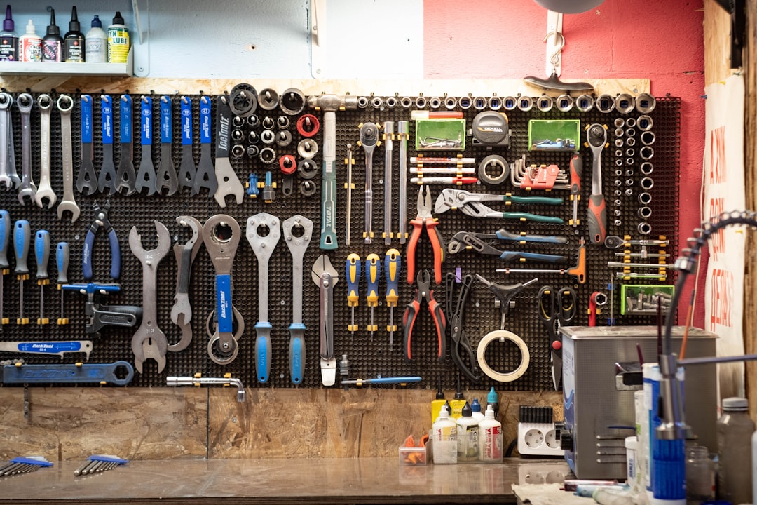 Workbench pegboard filled with wrenches, screwdrivers, pliers, and other hand tools organized by size and type in a workshop.